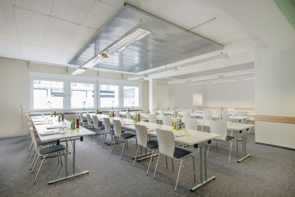 Moderner Tagungsraum mit vielen Tischen und Stühlen und Blick nach draußen