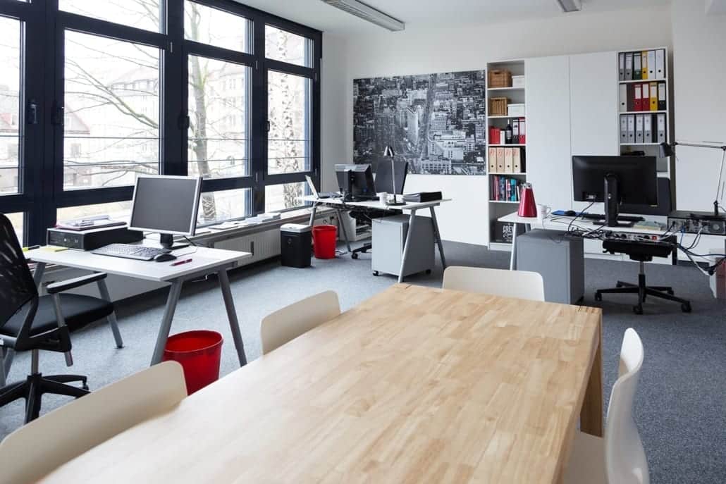 Hellbeleuchteter Raum mit Arbeitsplätzen und einem großem Meetingtisch