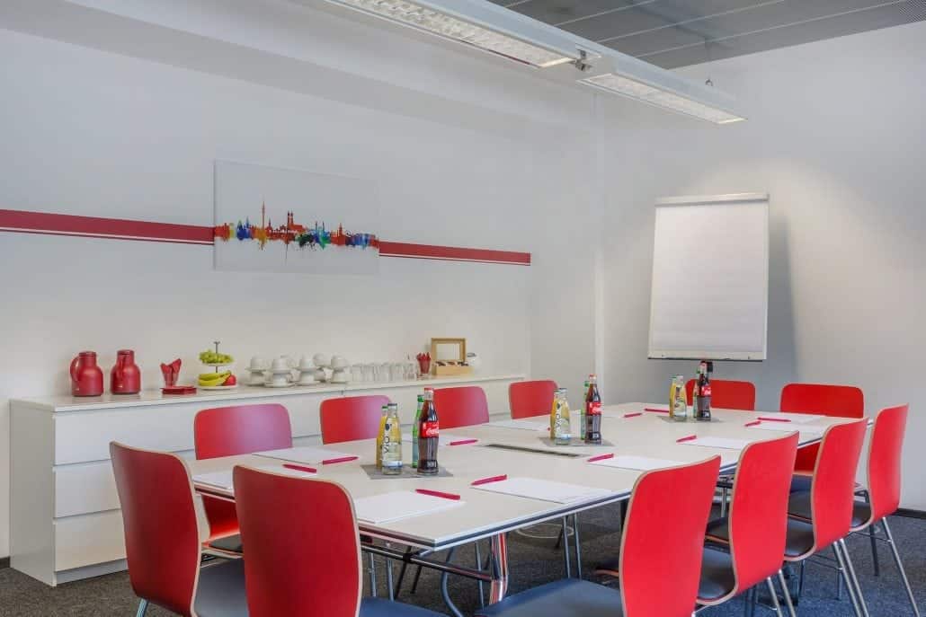 Meetingraum mit roten Stühlen an einem großem Konferenztisch mit einem Flipchart